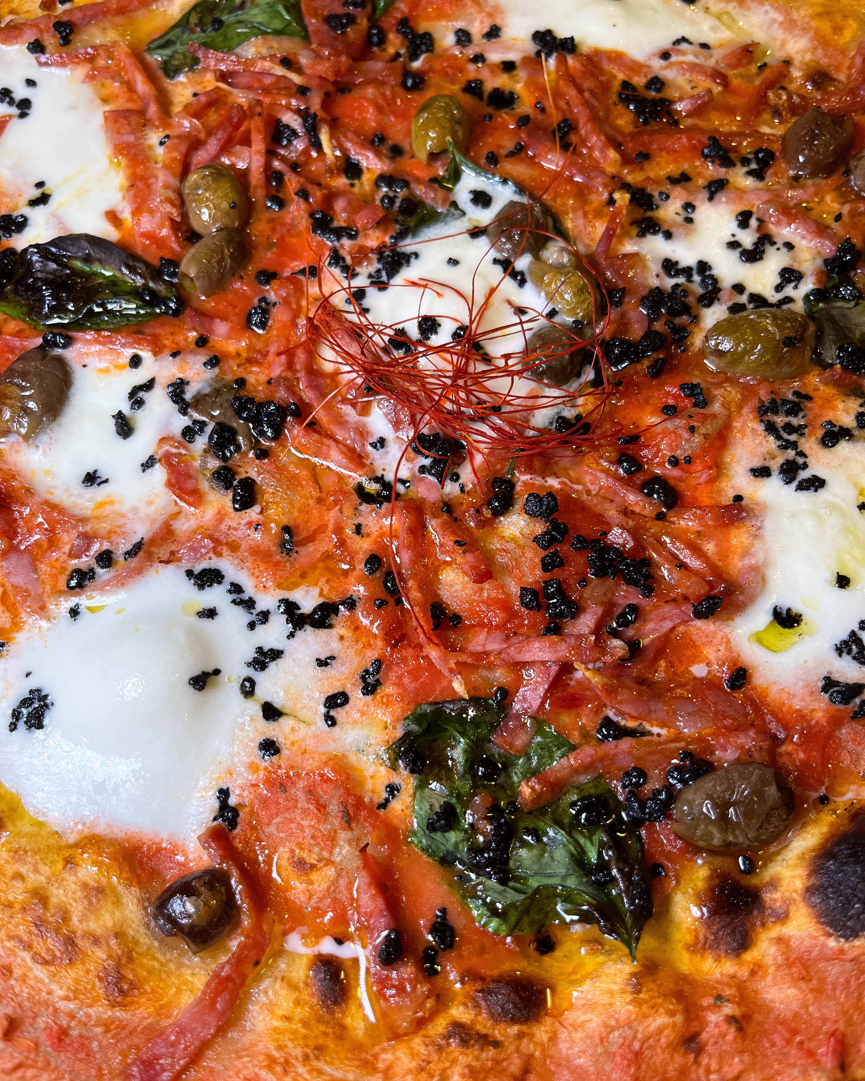 Pizza gourmet con ingredienti freschi e basilico su tavolo in legno